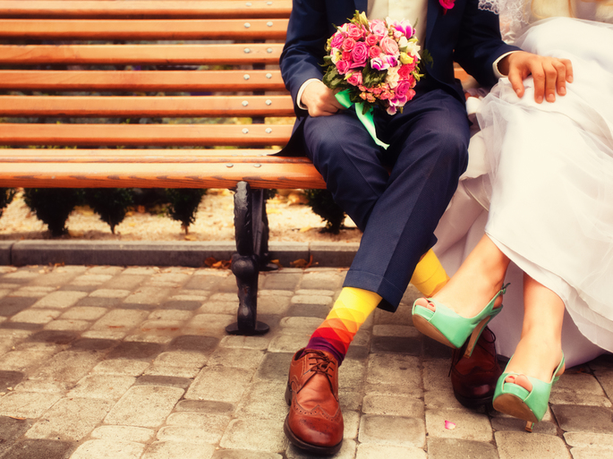 Noiva e noivo em roupas brilhantes sentados em um banco.