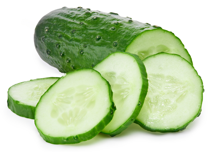 Fruto cilíndrico, verde escuto, de interior branco com sementes, cortado em fatias isoladas no fundo branco