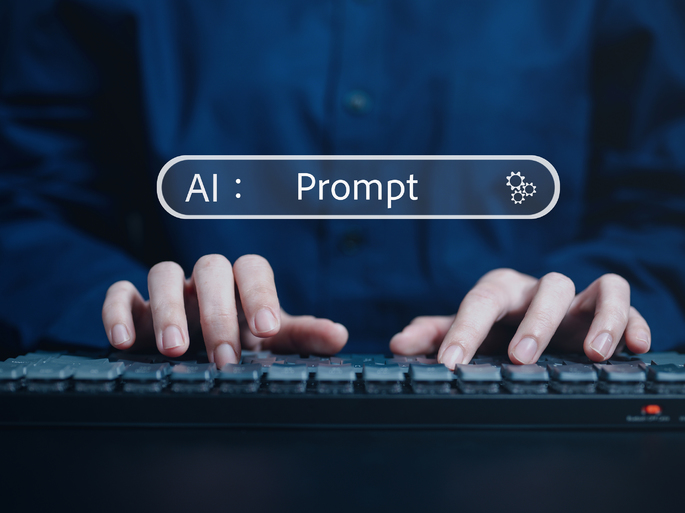 A imagem tem no centro um teclado exibindo um campo de texto. No centro da imagem, a palavra “Prompt” está visível, dentro deste campo, indicando que a parte assinalada corresponde ao prompt. Um teclado de computador está abaixo da palavra prompt e sugere a ideia de digitação assistida por uma AI (inteligência artificial) avançada. A imagem traz consigo a ideia de interação imediata entre uma pessoa e um programa de inteligência artificial por meio de prompts de texto.